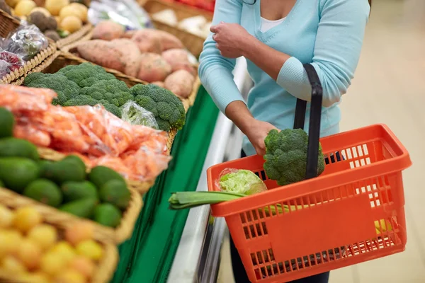 Woman with basket buying broccoli at grocery store — Stock Photo, Image