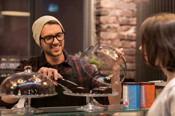 Man or barman with cakes serving customer at cafe — Stock Photo, Image
