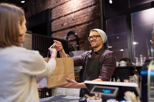 Vrouw neemt papieren zak van verkoper in cafe — Stockfoto