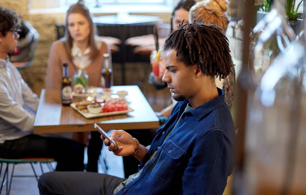 Человек со смартфоном и друзьями в ресторане — стоковое фото
