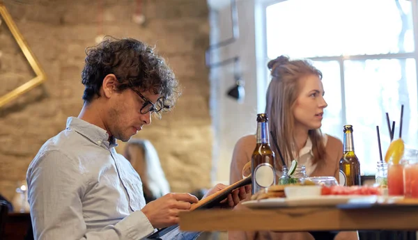 Happy friends looking to menu at restaurant — Stock Photo, Image