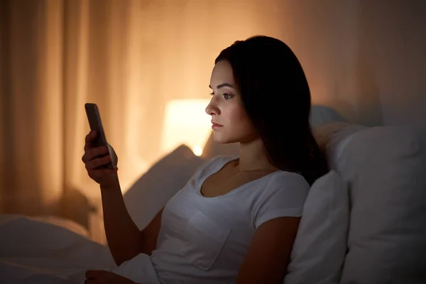 Jeune femme avec smartphone au lit la nuit — Photo