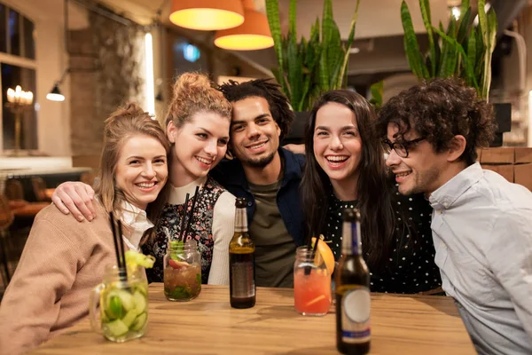 Amigos felizes com bebidas no bar ou café — Fotografia de Stock