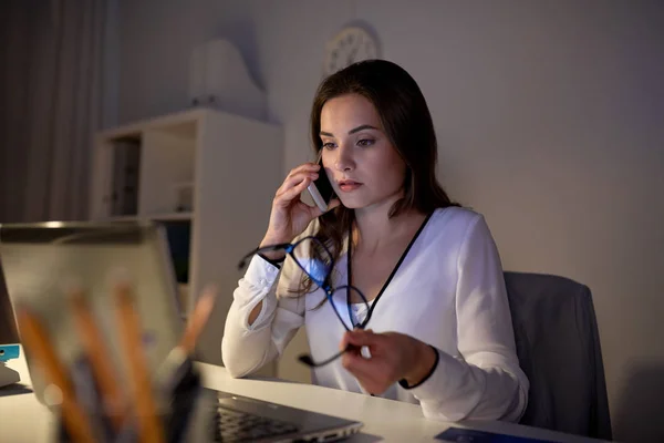 Mujer con portátil llamando en el teléfono inteligente en la oficina —  Fotos de Stock