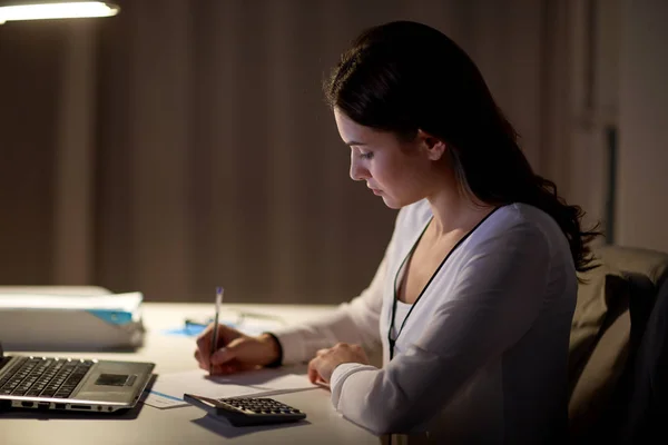Femme avec calculatrice et papiers au bureau de nuit — Photo