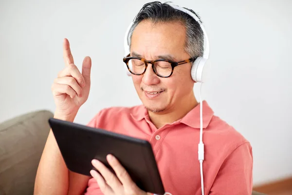 Hombre con tablet PC y auriculares en casa —  Fotos de Stock