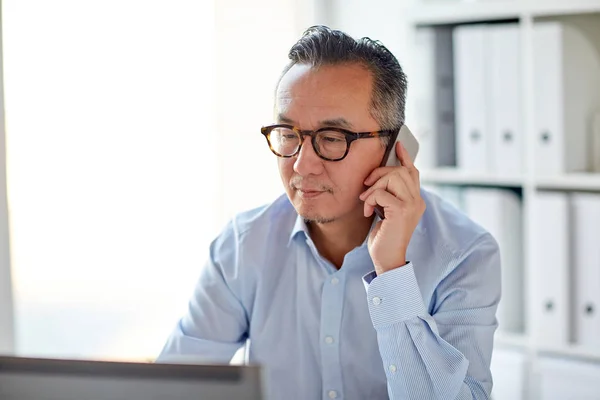 Homem de negócios com laptop chamando no smartphone — Fotografia de Stock