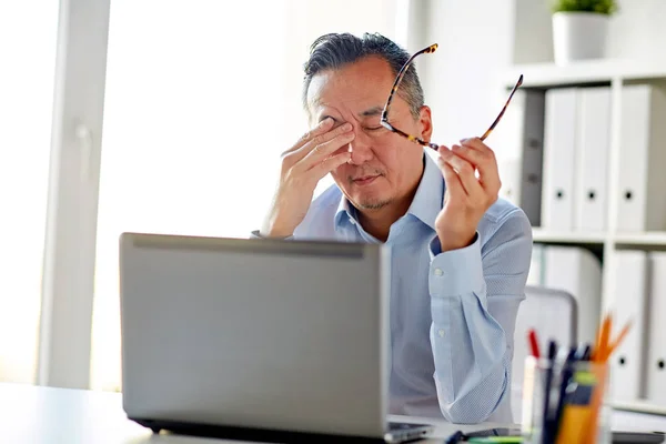 Moe zakenman met glazen op laptop in kantoor — Stockfoto