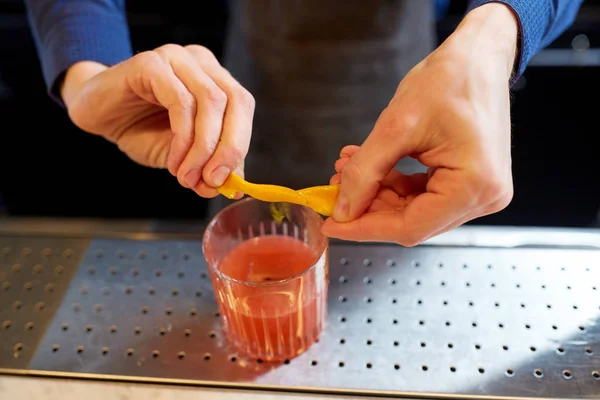 Barista con bicchiere di cocktail e buccia d'arancia — Foto Stock