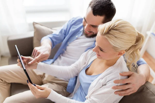Sorridente coppia felice con tablet pc a casa — Foto Stock