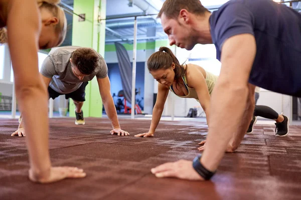 Groep van mensen die rechte arm plank in sportschool — Stockfoto