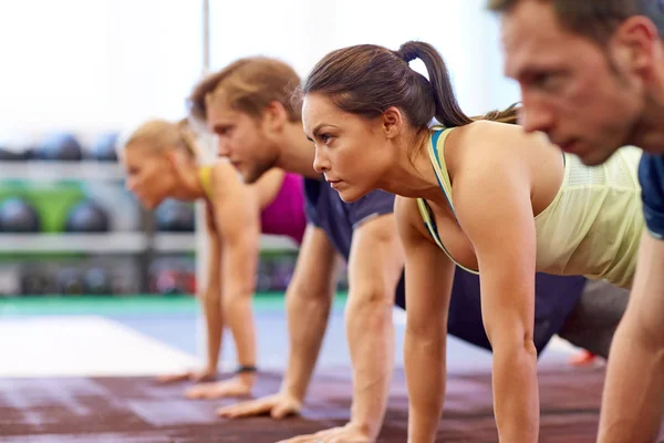 Gruppo di persone che fanno braccio dritto tavola in palestra — Foto Stock