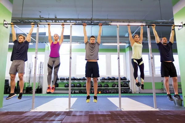 Grupp människor hänger på horisontell bar i gymmet — Stockfoto