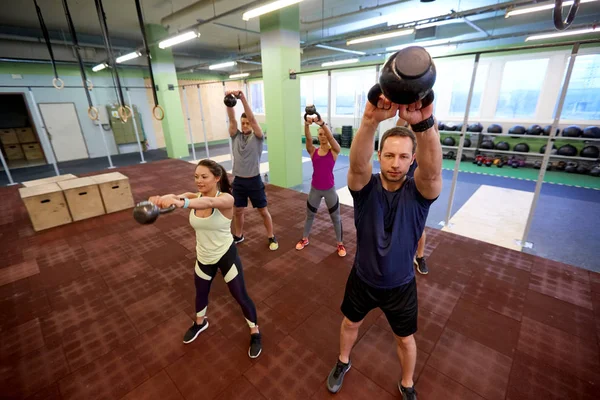 Grupp människor med kettlebells träning i gym — Stockfoto