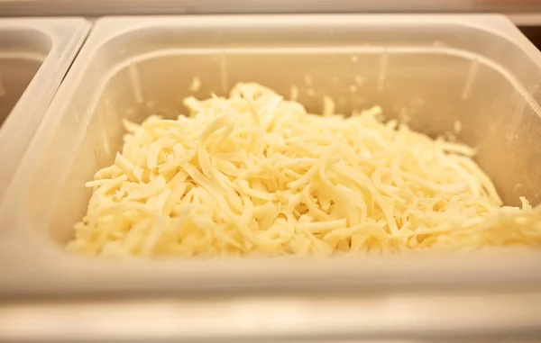 Contenedor con queso rallado en la cocina del restaurante —  Fotos de Stock