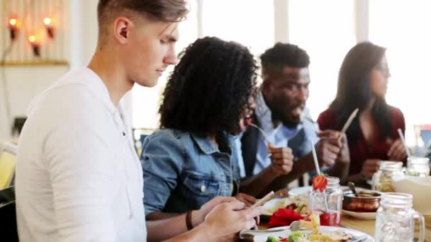 Hombre con smartphone y amigos en el restaurante — Vídeos de Stock