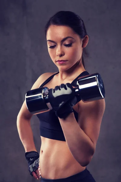 Mujer joven flexionando los músculos con pesas en el gimnasio —  Fotos de Stock