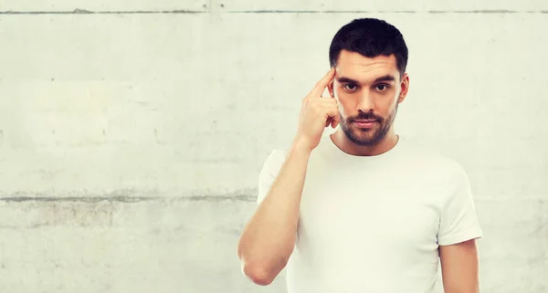 Mann mit Finger auf Tempel über graue Wand — Stockfoto