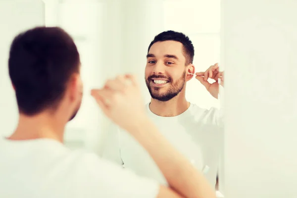 Man cleaning ear with cotton swab at bathroom — Stock Photo, Image