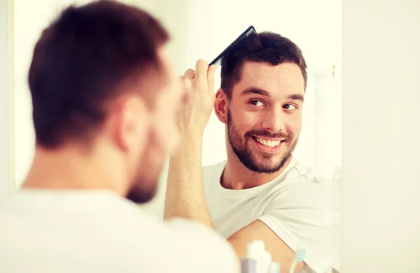 Šťastný muž kartáč na vlasy s hřebenem v koupelně — Stock fotografie