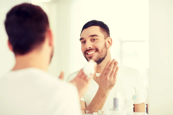 Uomo felice che applica schiuma da barba allo specchio del bagno — Foto Stock