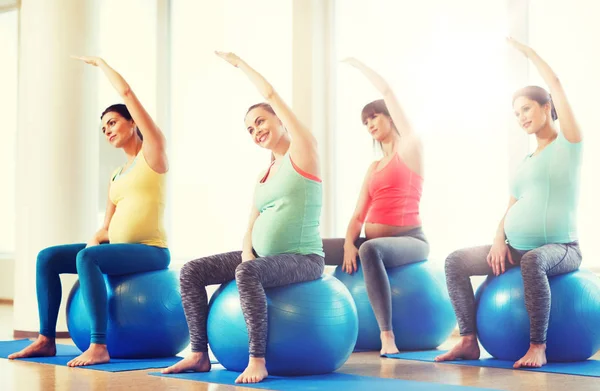 Felici donne incinte che esercitano sul fitball in palestra — Foto Stock