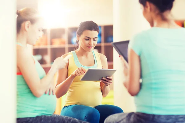 Gelukkig zwangere vrouwen met gadgets in sportschool — Stockfoto