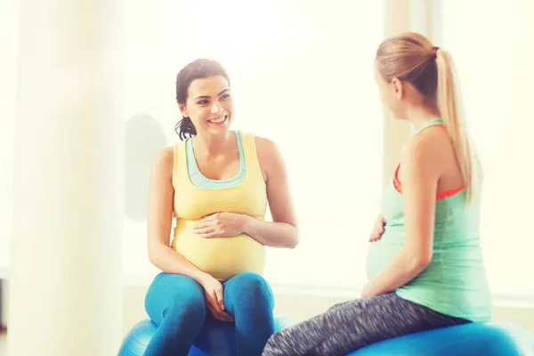 Two happy pregnant women sitting on balls in gym — Stock Photo, Image