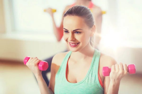 Lachende vrouw met halters trainen in de sportschool — Stockfoto