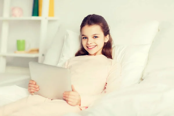 Glückliches Mädchen zu Hause mit Tablet-PC im Bett liegend — Stockfoto