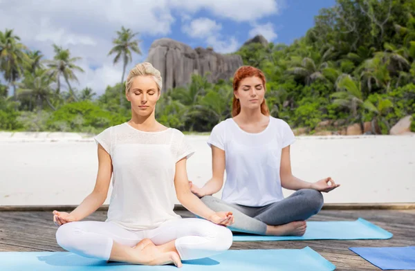 Женщины медитируют в позе лотоса йоги на открытом воздухе — стоковое фото