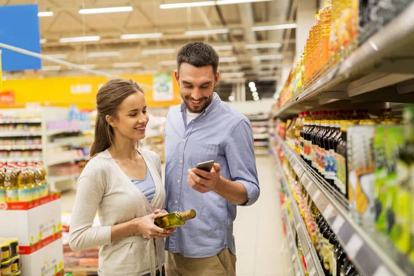 Met smartphone kopen van olijfolie bij supermarkt (echt) paar — Stockfoto