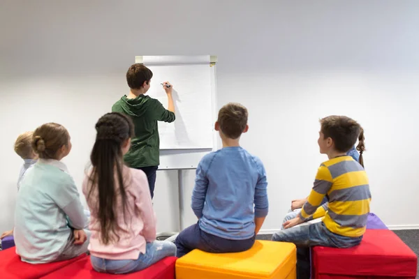 Student pojke med markör skriva på flip board — Stockfoto