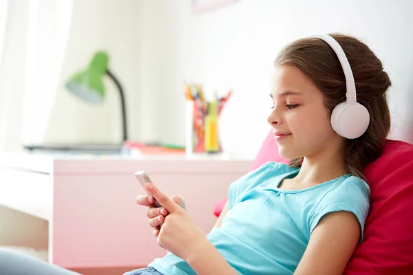 Happy girl with smartphone and headphones at home — Stock Photo, Image