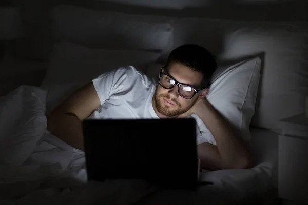 Jonge man met laptop in bed thuis slaapkamer — Stockfoto