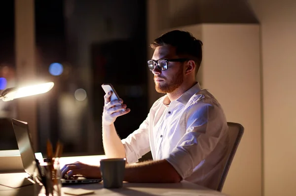 Zakenman texting op smartphone bij nacht kantoor — Stockfoto
