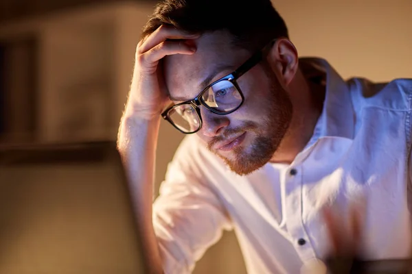 Hombre de negocios con portátil pensando en la oficina de noche —  Fotos de Stock