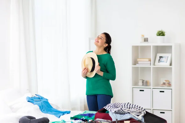 Lycklig kvinna med hatt packar resväskan hemma — Stockfoto