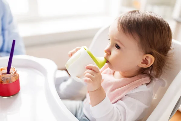 赤ちゃんは、ハイチェア自宅でカップを口から飲む — ストック写真