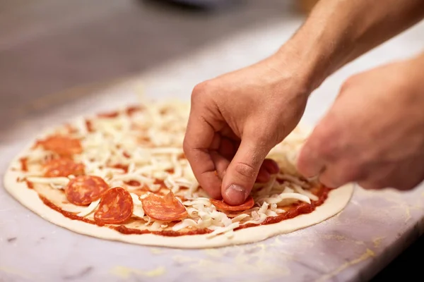 厨师手添加意大利腊肠披萨的披萨店 — 图库照片