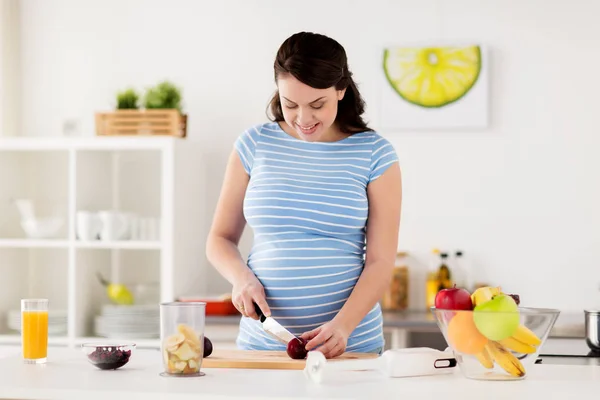 Kobieta w ciąży do krojenia owoców w domu kuchnia — Zdjęcie stockowe
