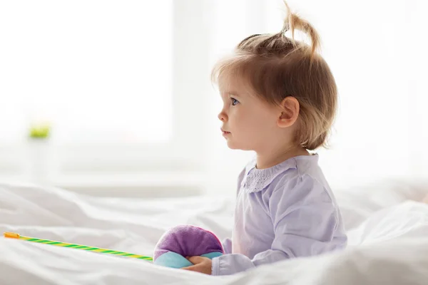 Encantadora niña con juguetes en la cama en casa — Foto de Stock