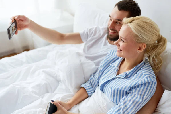 Casal feliz com smartphone levando selfie em casa — Fotografia de Stock