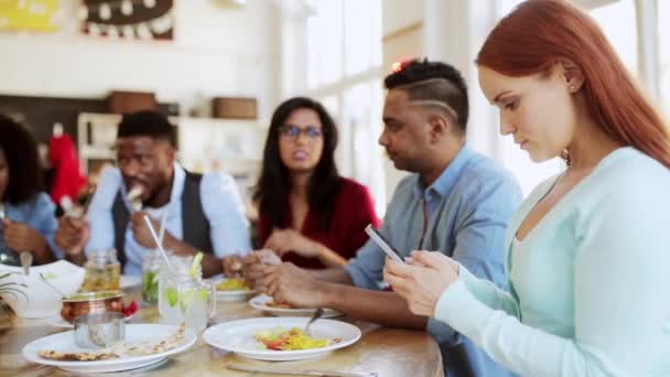 Mulher com smartphone e amigos no restaurante — Vídeo de Stock