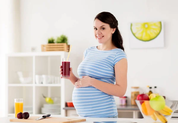 Happy pregnant woman drinking juice at home — Stock Photo, Image