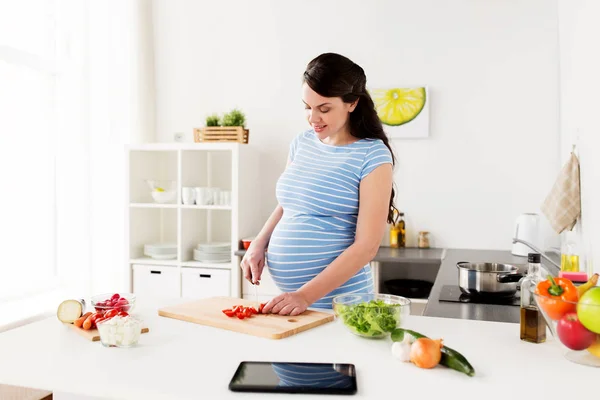 Pregnant woman cooking vegetables at home — Stock Photo, Image