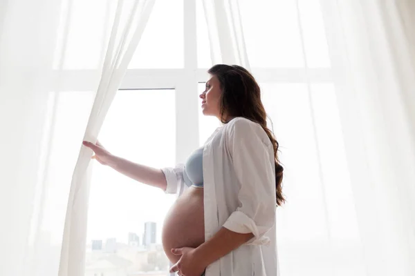 Счастливая беременная женщина с большим животиком дома — стоковое фото