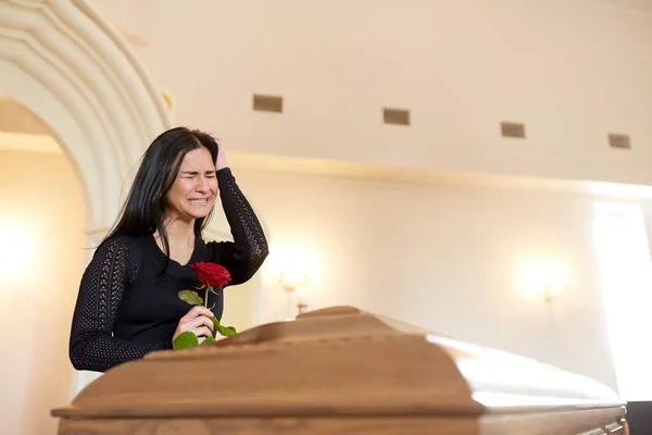 Weinende Frau mit roter Rose und Sarg bei Beerdigung — Stockfoto