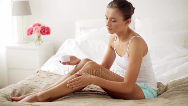 Hermosa mujer aplicando crema a sus piernas en casa — Vídeo de stock
