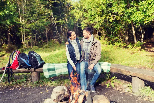 Pasangan bahagia duduk di bangku dekat api kamp — Stok Foto